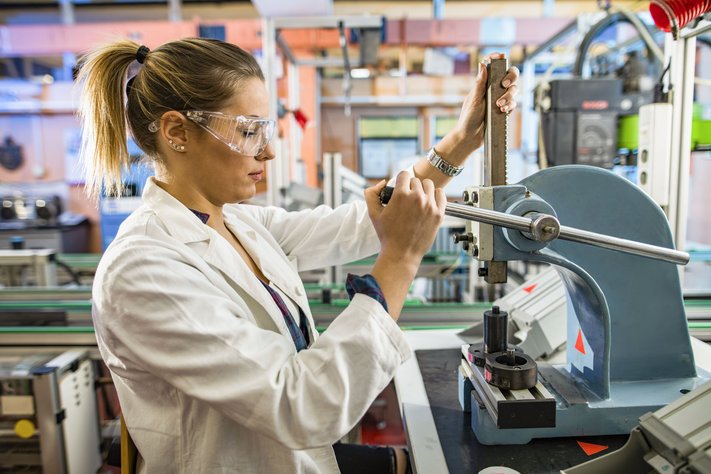 A young female lab worker working on a machine in laboratory.
