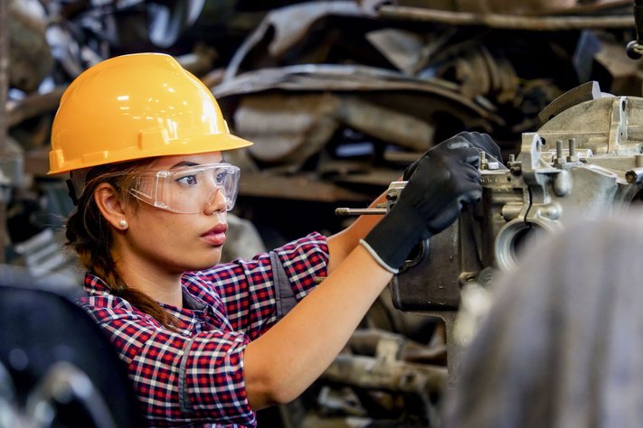 A young asian engineer woman working with metal machine.