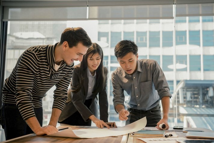 Three young architects discussing project in modern office.