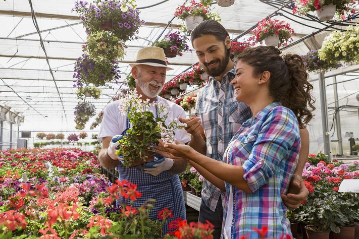 A couple admire flowers with greenhouse florist.