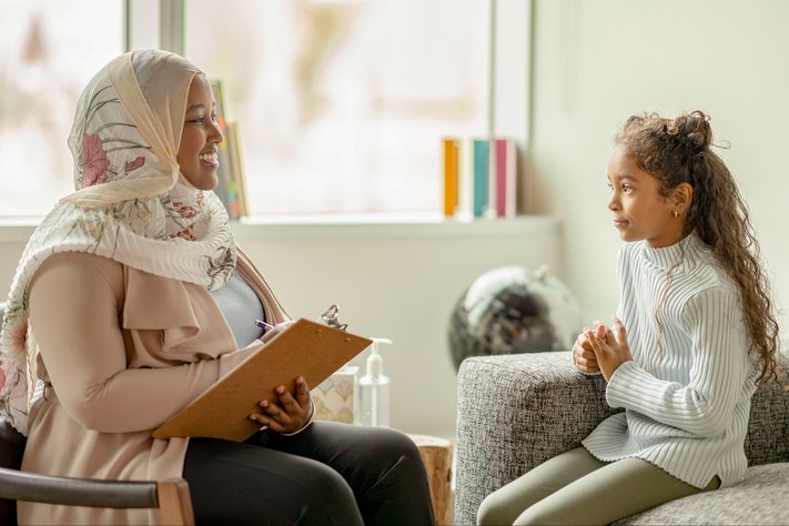 A female researcher interviews young girl in lounge setting.