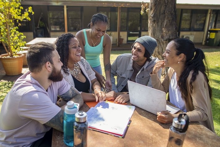 Young professionals discuss at an outdoor table.