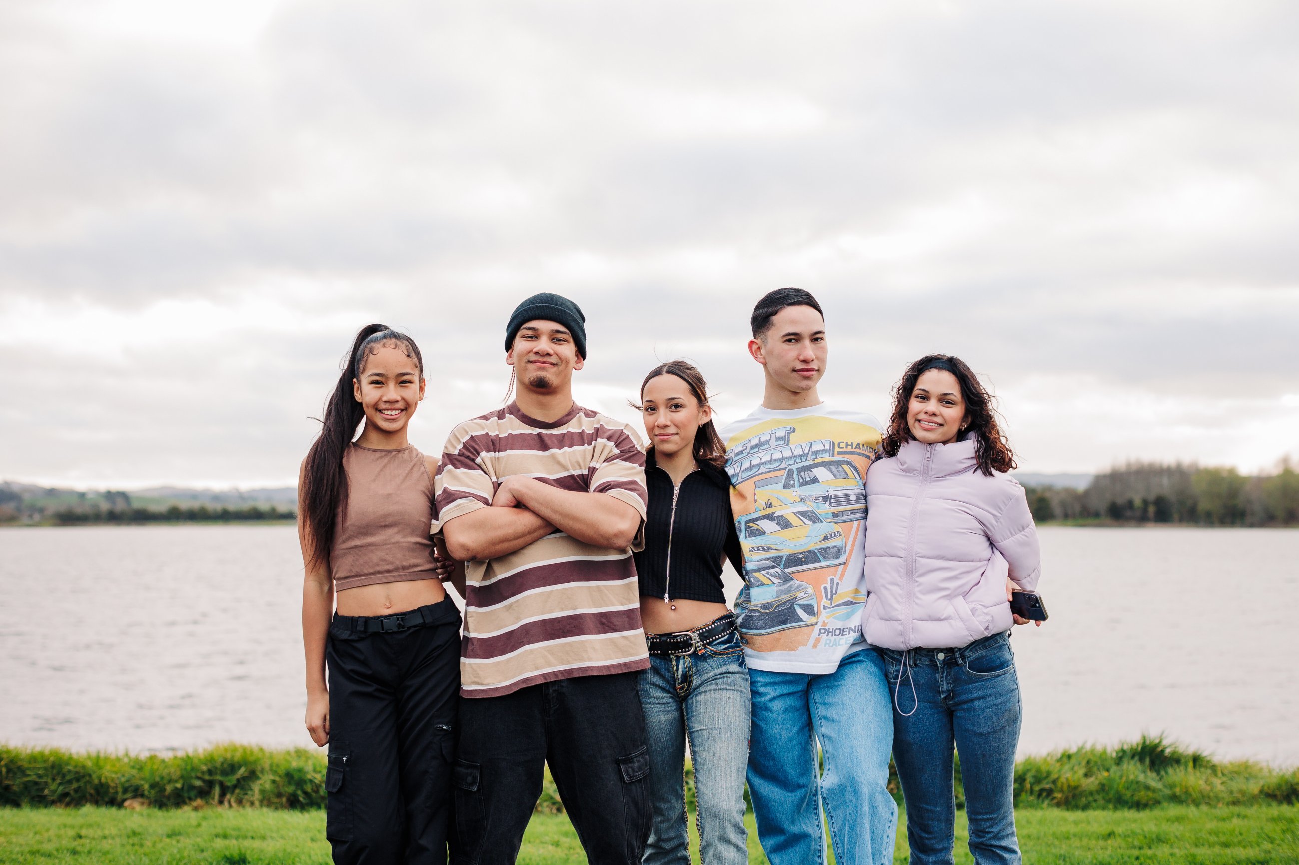 5 teenagers stand by the water looking at the camera.