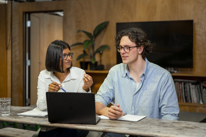 A mechanic and male trainee working underneath a car together