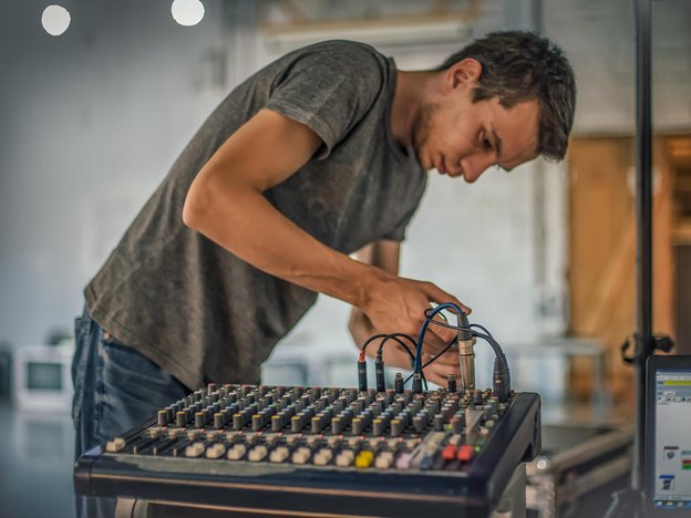 A man connects a cord to a sound system machine.