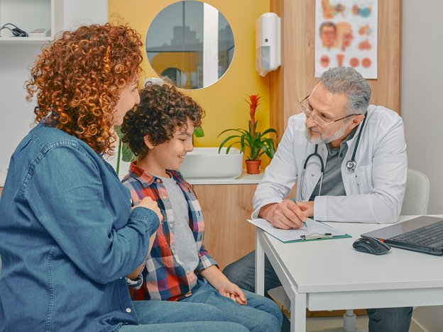 A medical professional talks to a parent or caregiver and their child in a modern health centre.