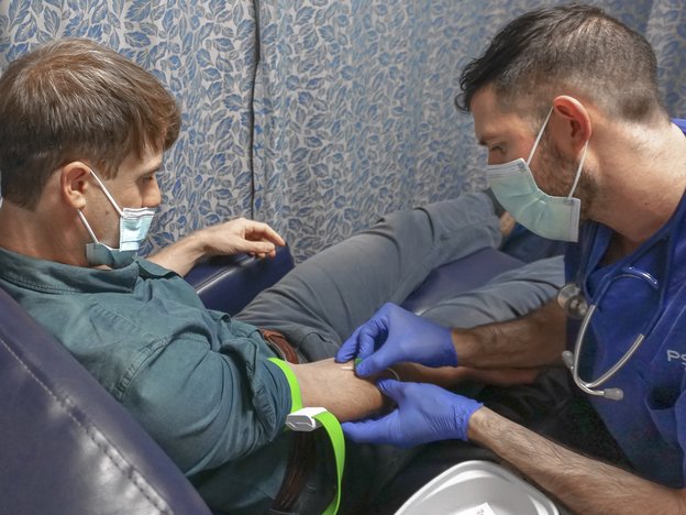 A man takes a blood sample from a young boy.