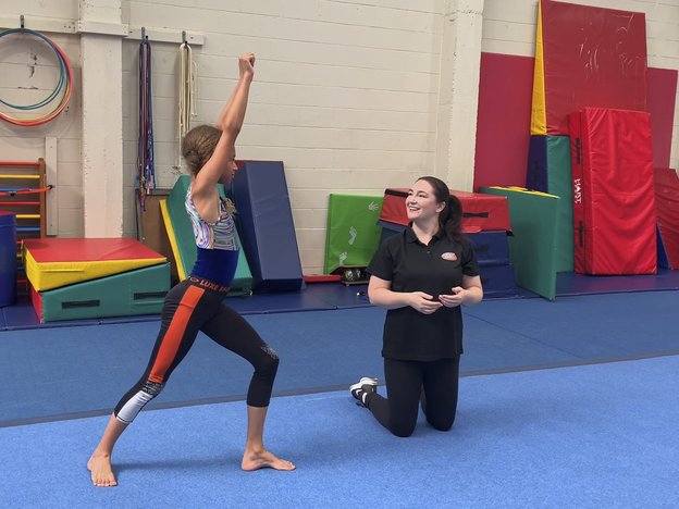 A female raises her arms and stretches while another female watches.