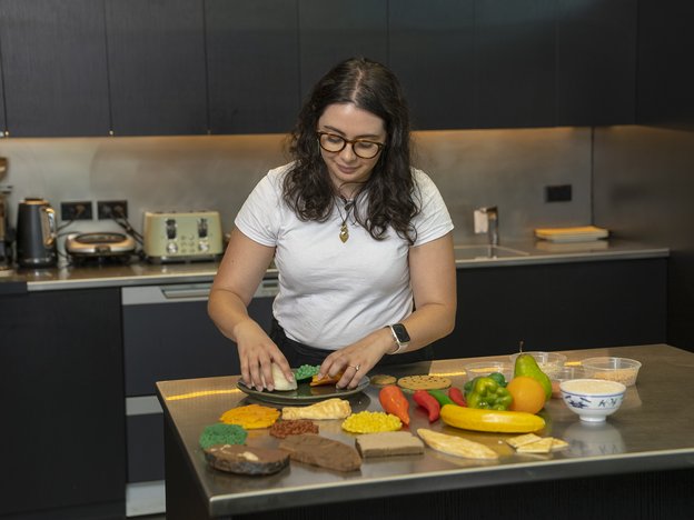 A woman prepares plastic food on a table in a kitchen.