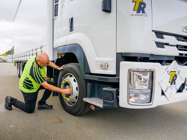 A man inspects the wheel of a heavy truck.