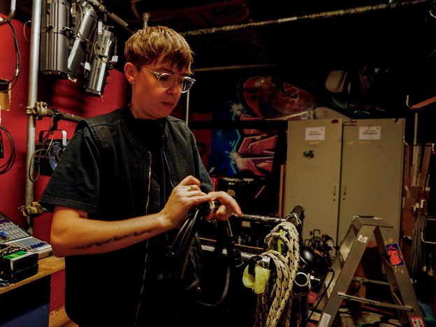 A man holds stage lighting equipment. It's a gold and yellow light.