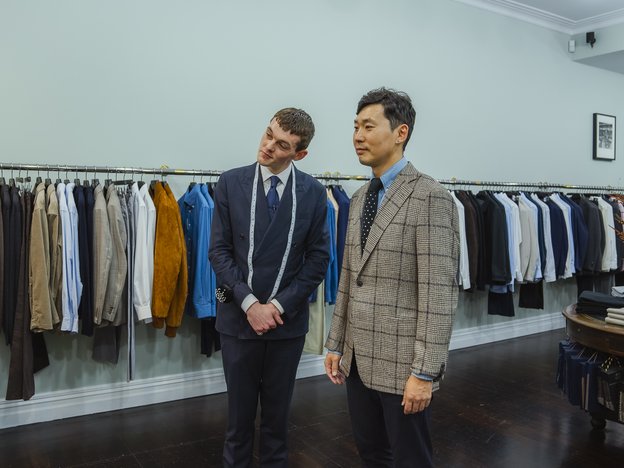 Two males stand next to each other and wear suits.