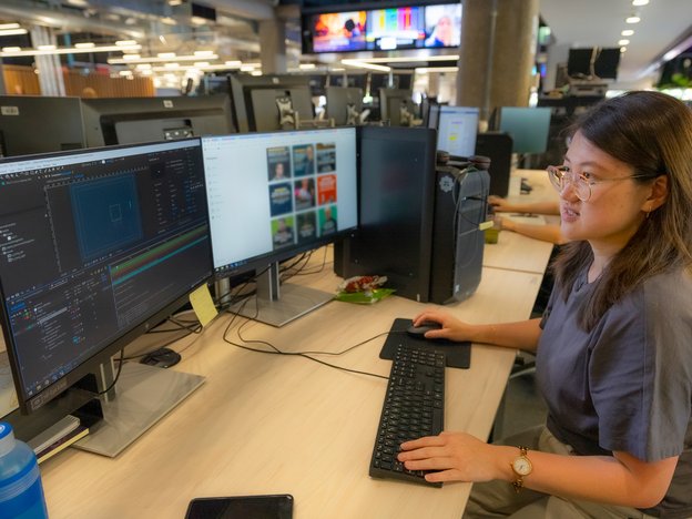 A female looks at a computer screen and sits at a desk.