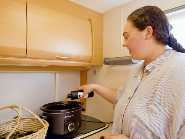 E tāhoro hinu ana he wahine ki roto i tētahi kōhua nui, ā, kei roto kerewēne ia. Kei te taha o te kōhua he kete kī i te rau maroke.
