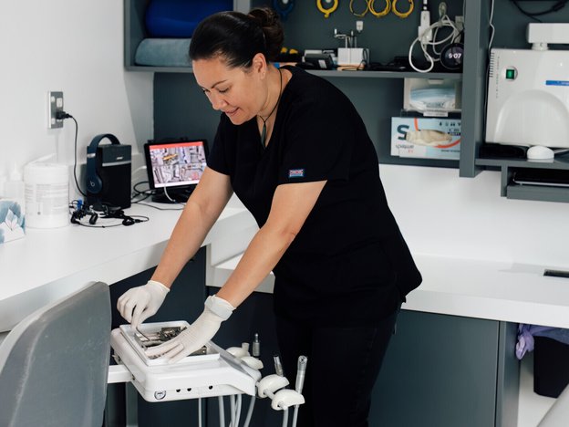 female clinical nurse specialist assembles some medical utensils in a nursing station. She is wearing a black uniform and white gloves.