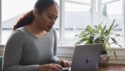 A woman uses a laptop sitting at a table.