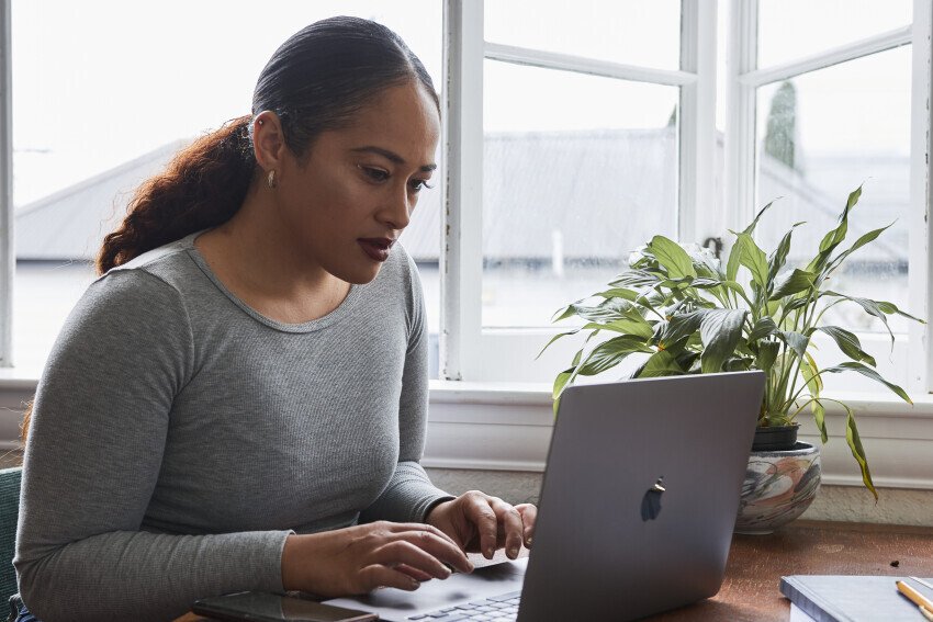 A woman uses a laptop sitting at a table.