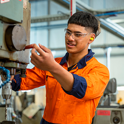 A young man using a machine in a factory.