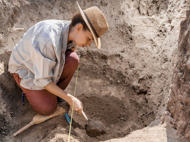 female archaeologist digging in the dirt