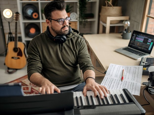 Music composer working in studio and composing on a keyboard