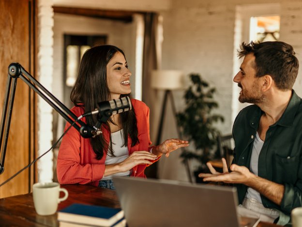 Two people record their podcast using a laptop and a microphone